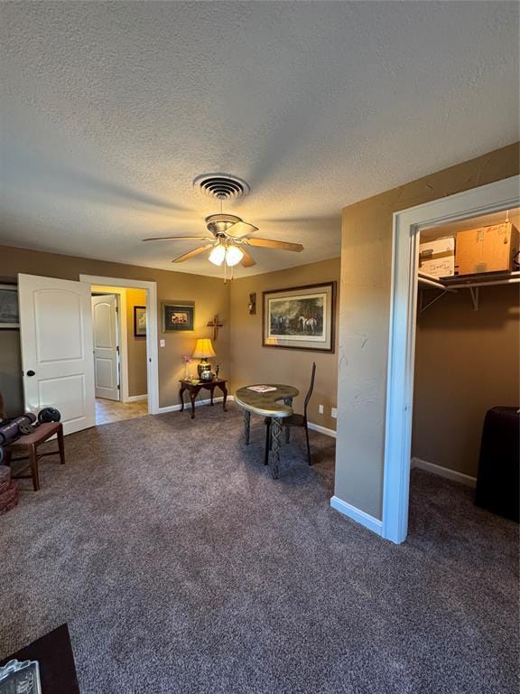 living area with ceiling fan, carpet floors, and a textured ceiling