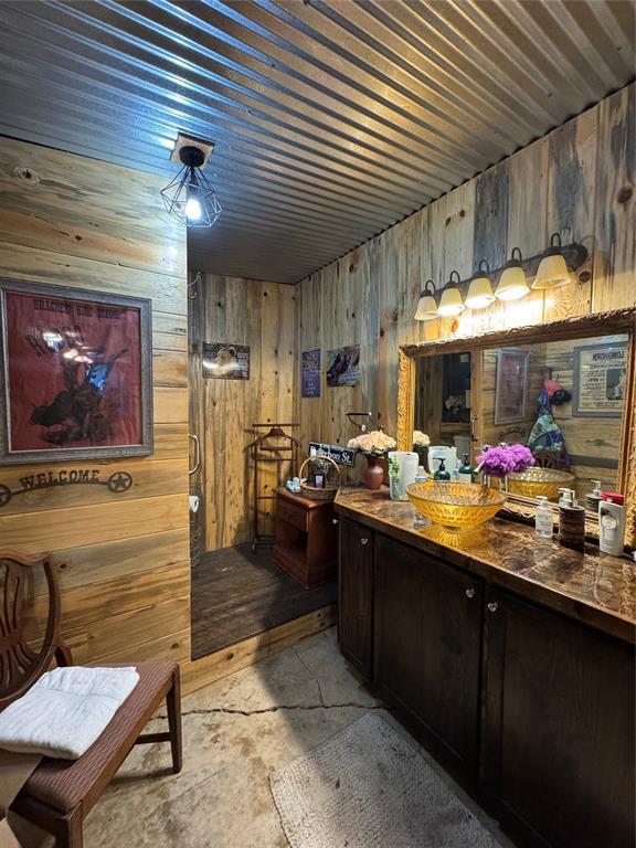 bathroom featuring dark brown cabinetry, wooden ceiling, and wood walls