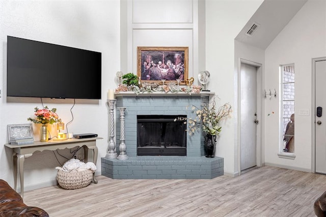 living room with lofted ceiling, a fireplace, and light hardwood / wood-style floors