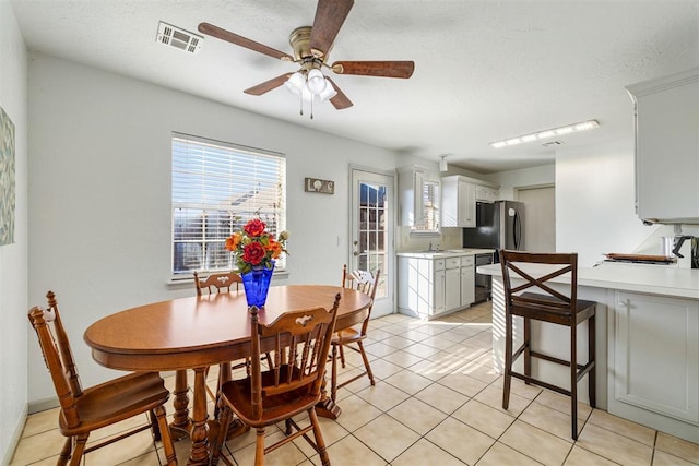 dining space featuring ceiling fan, a textured ceiling, and light tile patterned flooring