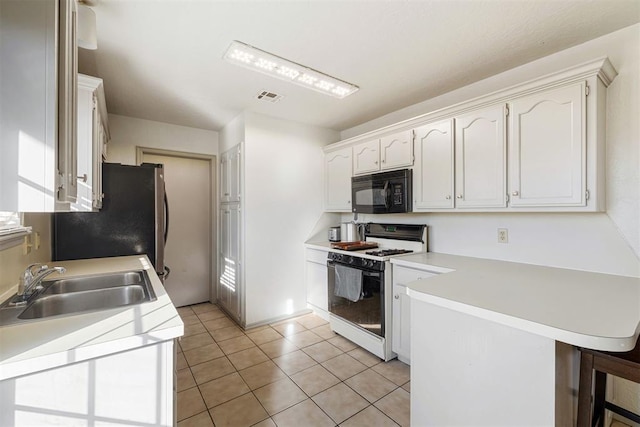 kitchen featuring light tile patterned flooring, sink, white cabinetry, white gas range, and kitchen peninsula