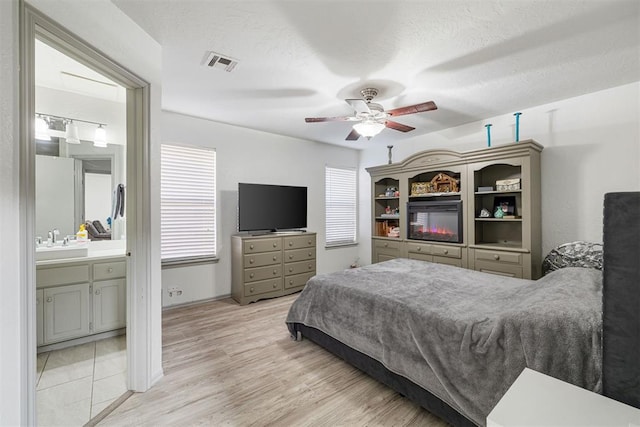 bedroom with ceiling fan, sink, a textured ceiling, and light hardwood / wood-style floors