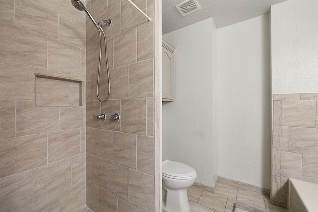 bathroom featuring a tile shower and toilet