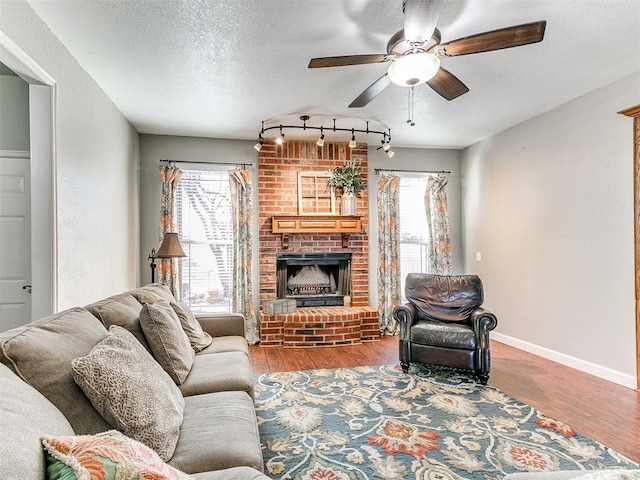 living room with a brick fireplace, a textured ceiling, hardwood / wood-style floors, and a healthy amount of sunlight