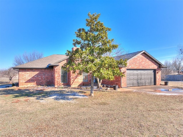 view of front of house with brick siding, an attached garage, a front lawn, a chimney, and driveway