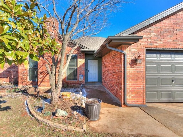 view of exterior entry with a garage and brick siding