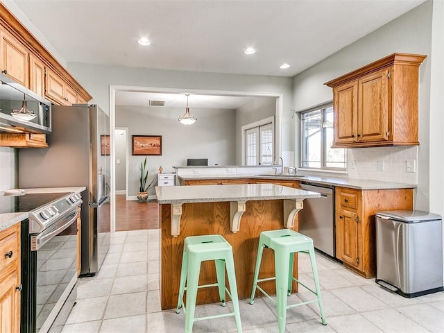 kitchen featuring visible vents, recessed lighting, appliances with stainless steel finishes, decorative backsplash, and a breakfast bar area