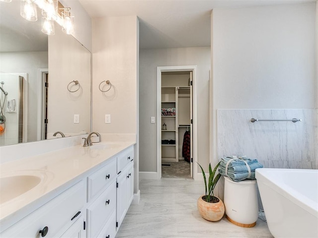 bathroom with a freestanding bath, a sink, a spacious closet, double vanity, and marble finish floor