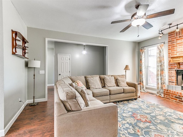 living room with a fireplace, dark wood finished floors, a textured ceiling, a ceiling fan, and baseboards