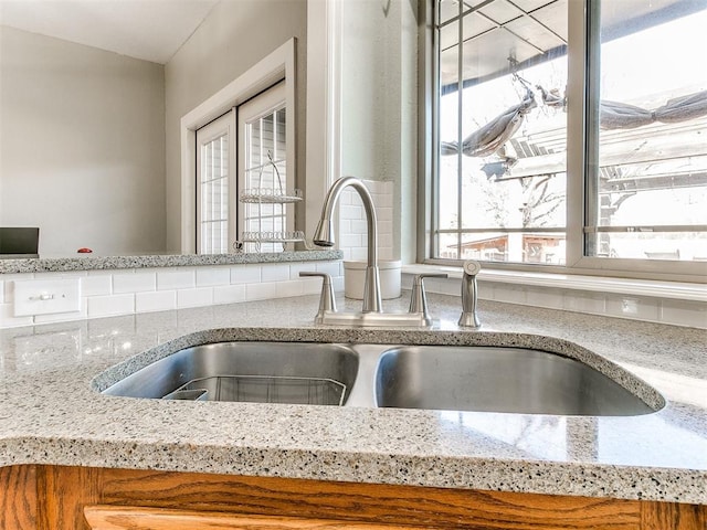 room details featuring brown cabinetry, light stone counters, and a sink