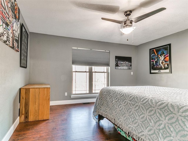 bedroom with a textured ceiling, a ceiling fan, visible vents, hardwood / wood-style floors, and baseboards
