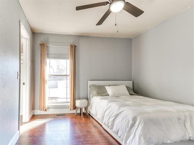 bedroom featuring baseboards, ceiling fan, and wood finished floors