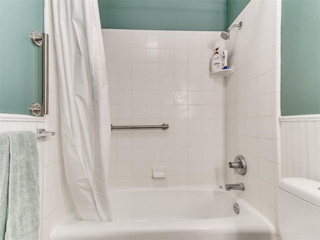 bathroom with shower / bath combination with curtain, wainscoting, and toilet