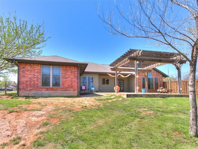 back of property with a pergola, a patio area, brick siding, and a yard