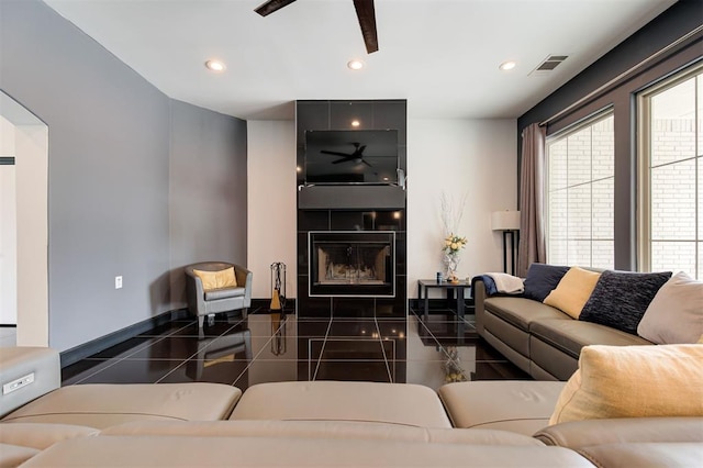 living room with a tiled fireplace and ceiling fan