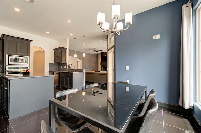 dining room featuring sink, ceiling fan with notable chandelier, and dark tile patterned flooring