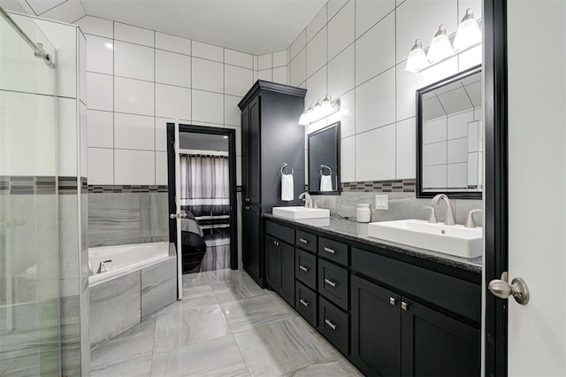 bathroom featuring tile walls, tiled tub, vanity, and tasteful backsplash