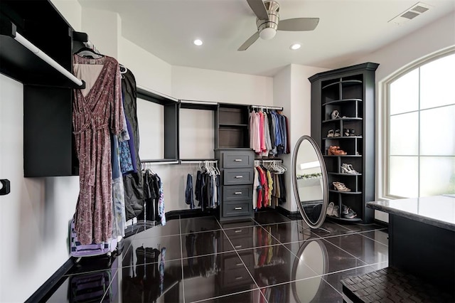 spacious closet with dark tile patterned flooring and ceiling fan