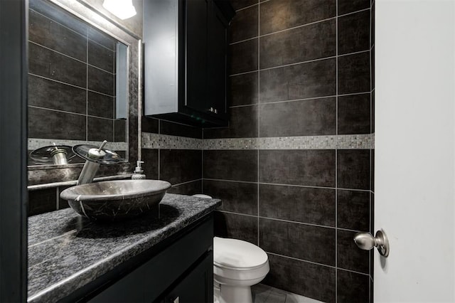 bathroom featuring vanity, toilet, and tile walls