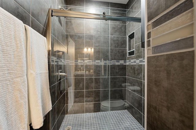 bathroom featuring toilet and a shower with shower door