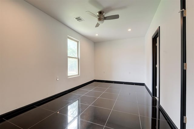 unfurnished room featuring ceiling fan and dark tile patterned flooring