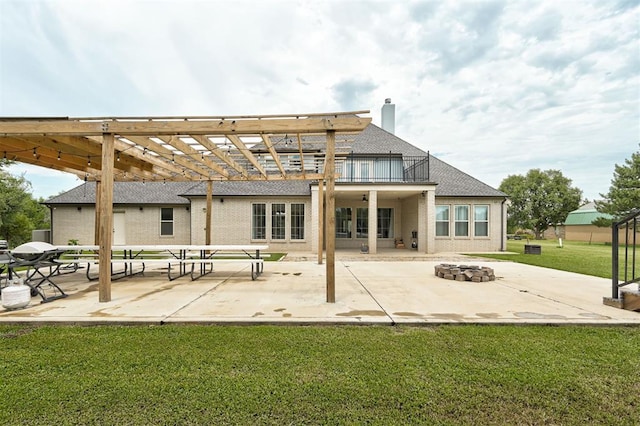 rear view of house featuring a patio area, a lawn, a balcony, and an outdoor fire pit