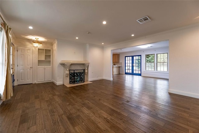 unfurnished living room with dark hardwood / wood-style flooring, ornamental molding, a fireplace, and french doors