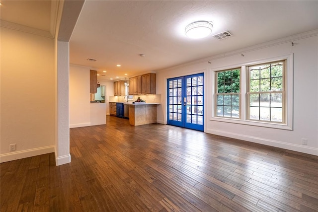 unfurnished living room with crown molding, dark hardwood / wood-style flooring, french doors, and a wealth of natural light