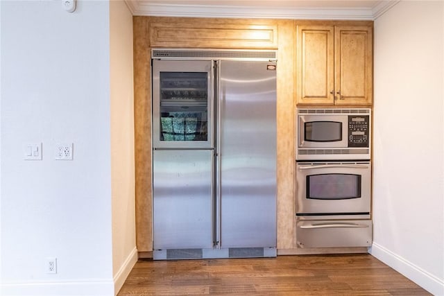 kitchen with built in appliances, light brown cabinetry, ornamental molding, and dark hardwood / wood-style floors