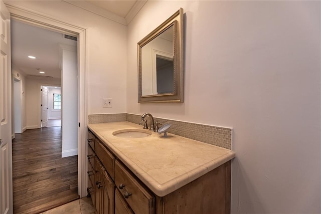 bathroom featuring vanity, wood-type flooring, and ornamental molding