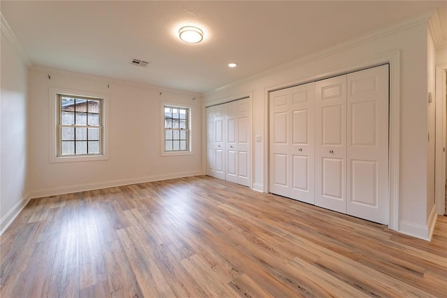 unfurnished bedroom featuring two closets, light hardwood / wood-style flooring, and ornamental molding