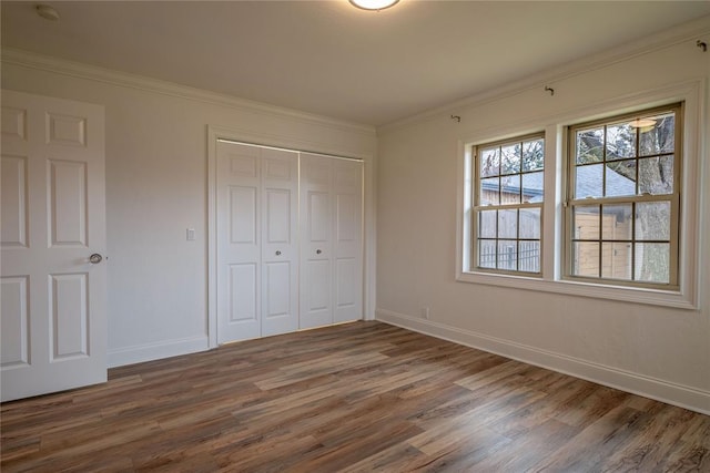 unfurnished bedroom with crown molding, dark hardwood / wood-style flooring, and a closet