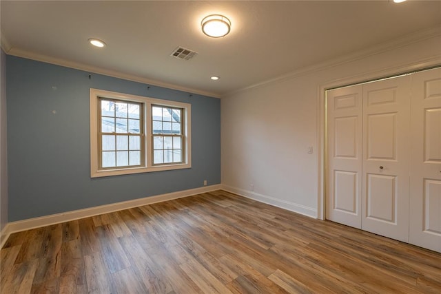 unfurnished bedroom featuring ornamental molding, hardwood / wood-style floors, and a closet