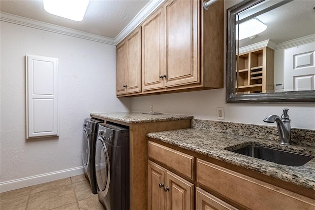 clothes washing area featuring cabinets, ornamental molding, sink, and washer and dryer