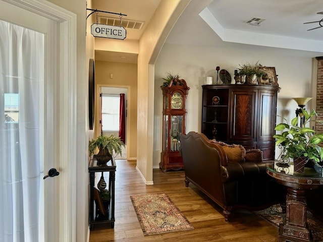 interior space with arched walkways, baseboards, visible vents, and light wood-style floors