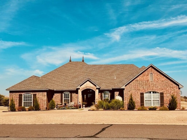 view of front of home with roof with shingles and brick siding