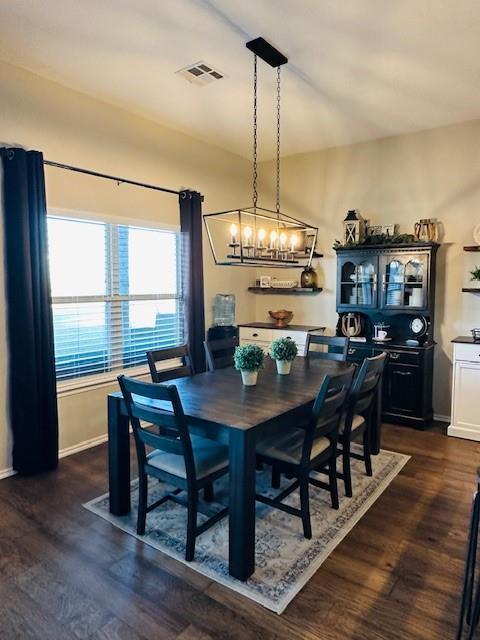 dining space with baseboards, visible vents, and dark wood-type flooring