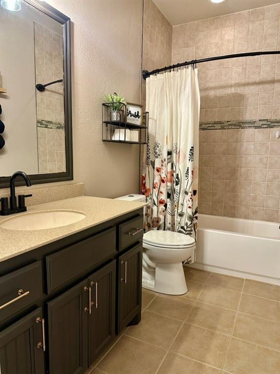 bathroom with vanity, tile patterned flooring, toilet, and shower / tub combo with curtain