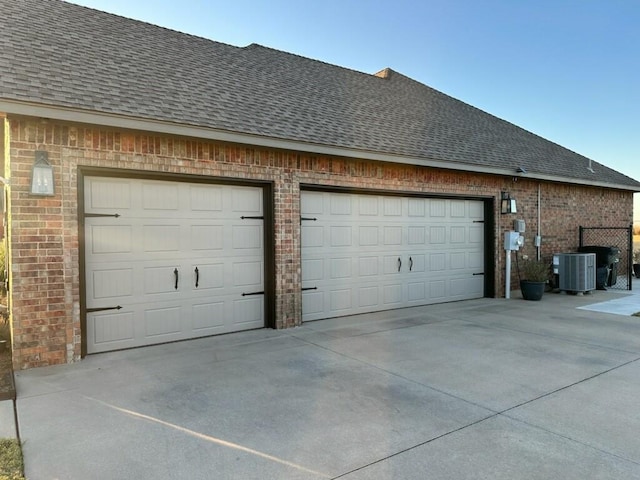 garage with concrete driveway and central AC