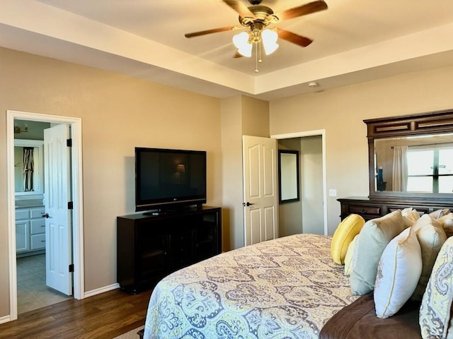 bedroom with dark wood-type flooring, ensuite bath, a ceiling fan, and baseboards