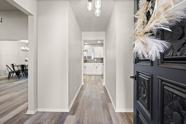 hallway featuring hardwood / wood-style flooring and a notable chandelier