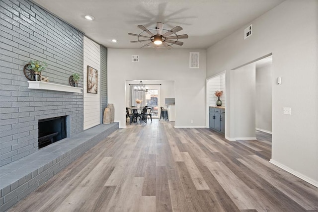 unfurnished living room with hardwood / wood-style floors, a brick fireplace, and ceiling fan