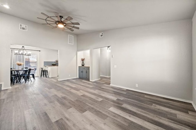 unfurnished living room with hardwood / wood-style flooring, lofted ceiling, and ceiling fan with notable chandelier