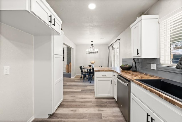 kitchen with decorative light fixtures, white cabinetry, dishwasher, sink, and wooden counters