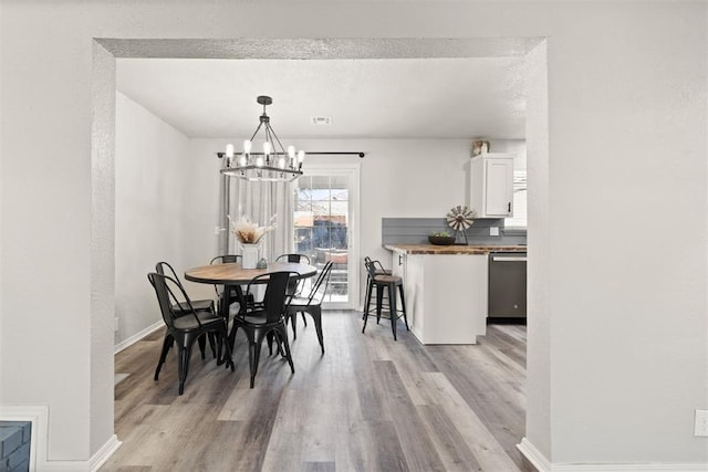 dining space featuring a chandelier, light hardwood / wood-style floors, and a textured ceiling