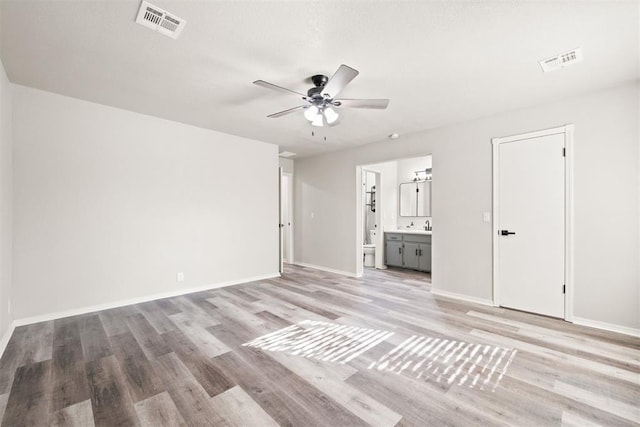 interior space with ceiling fan, connected bathroom, and light wood-type flooring