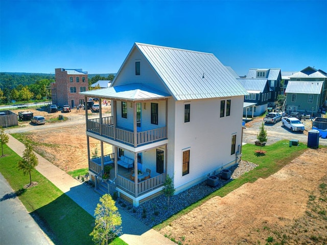 back of house with central AC unit, a balcony, and a porch