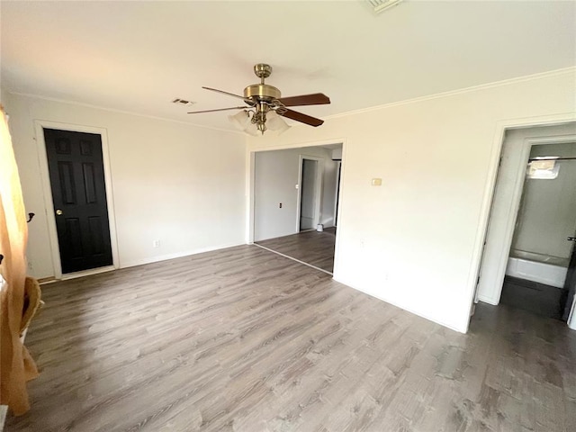 spare room with wood finished floors, a ceiling fan, and crown molding