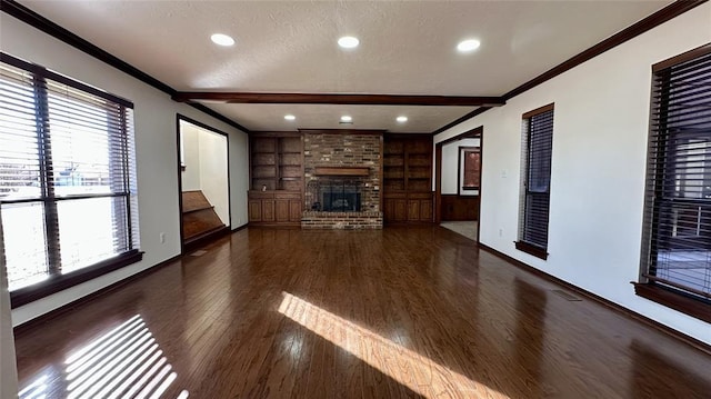 unfurnished living room with built in shelves, a brick fireplace, ornamental molding, dark hardwood / wood-style floors, and beam ceiling