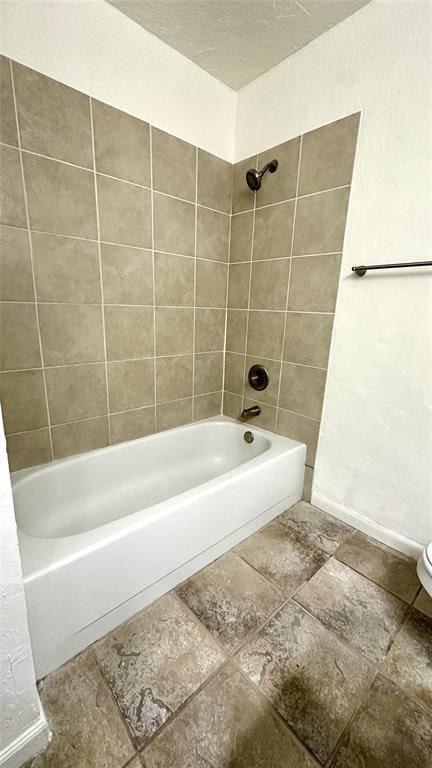 bathroom with tiled shower / bath, toilet, and a textured ceiling